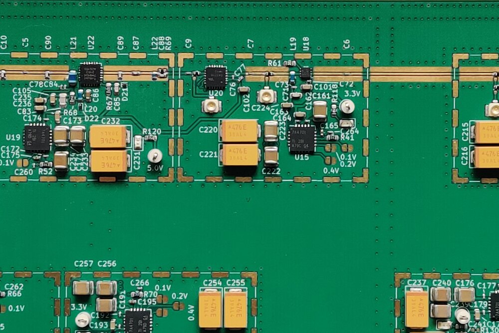 Close-up of a green RF circuit board showing power-management sections, tantalum capacitors and labelled voltage rails